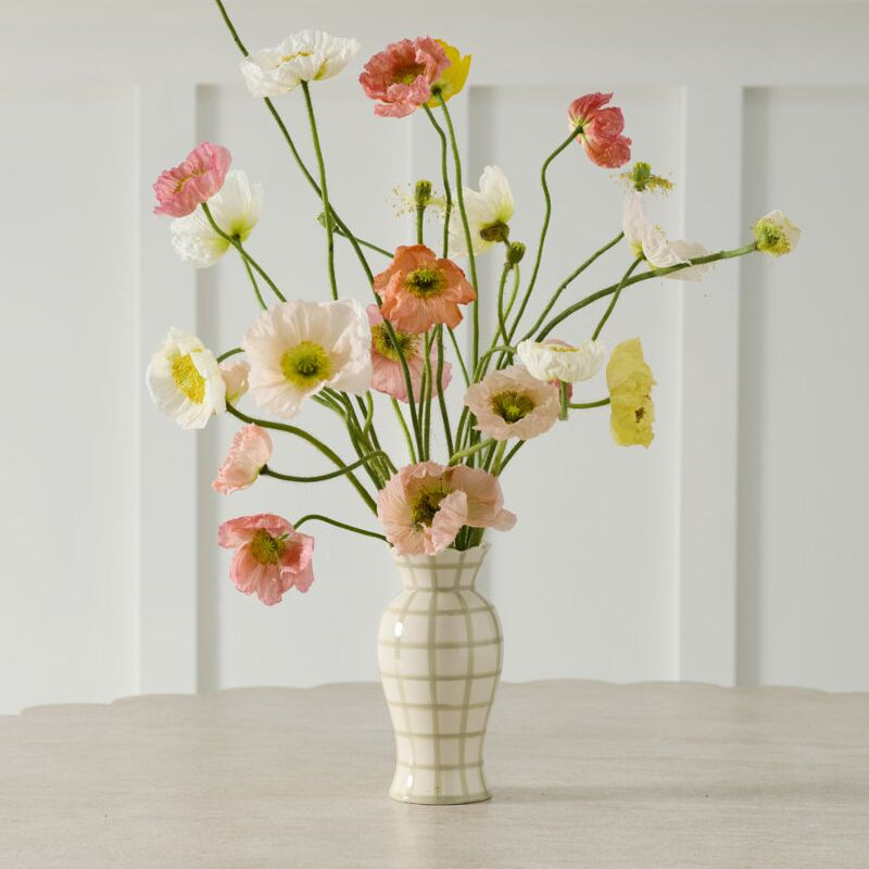 Vase with flowers on a wooden table against a white paneled wall