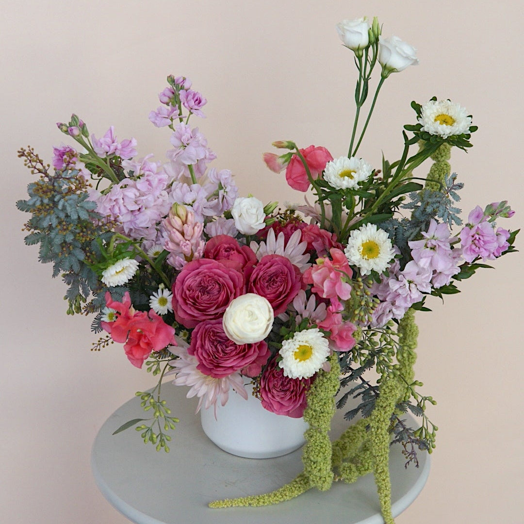 Colorful flower arrangement on a small round table against a plain background