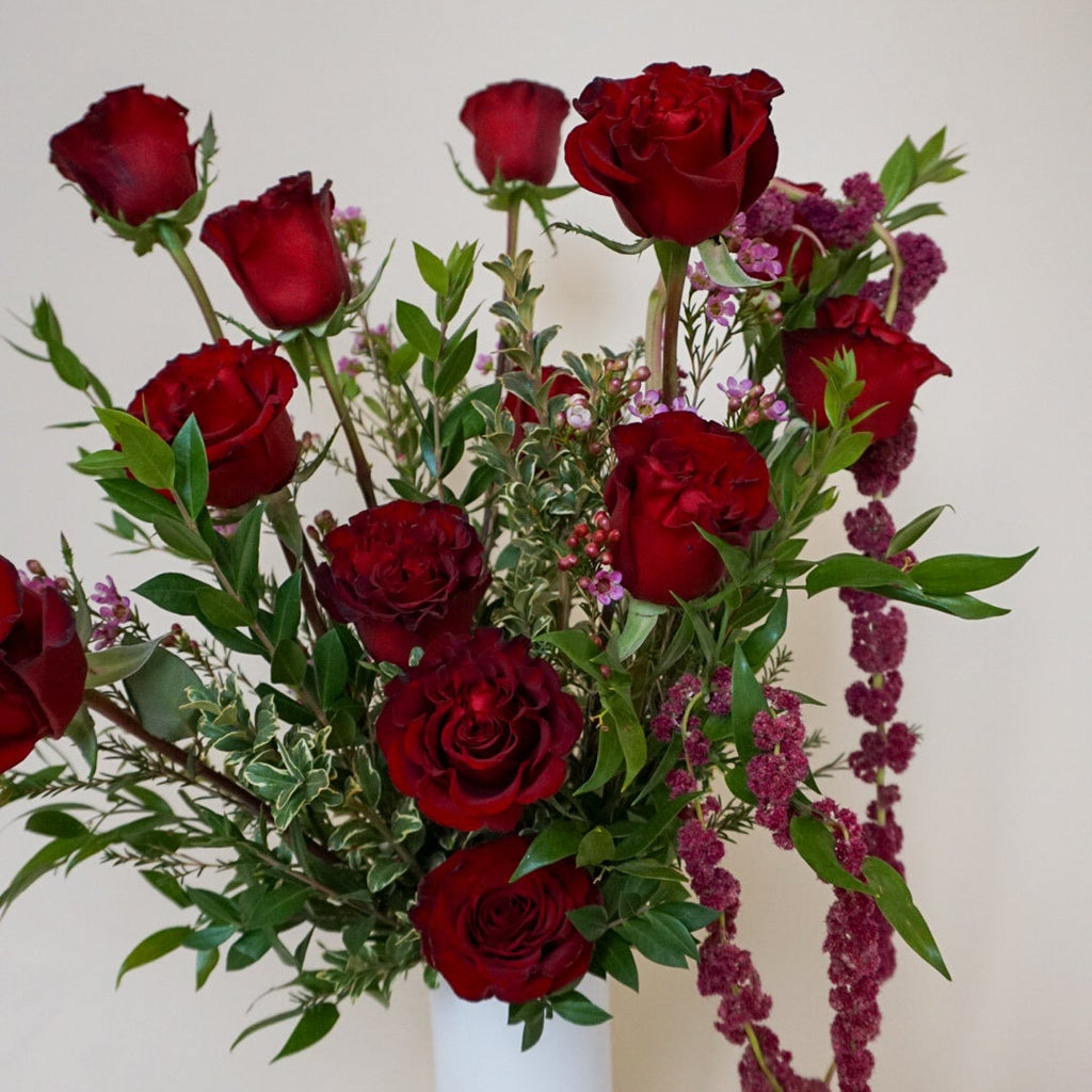 Bouquet of red roses with greenery on a light background