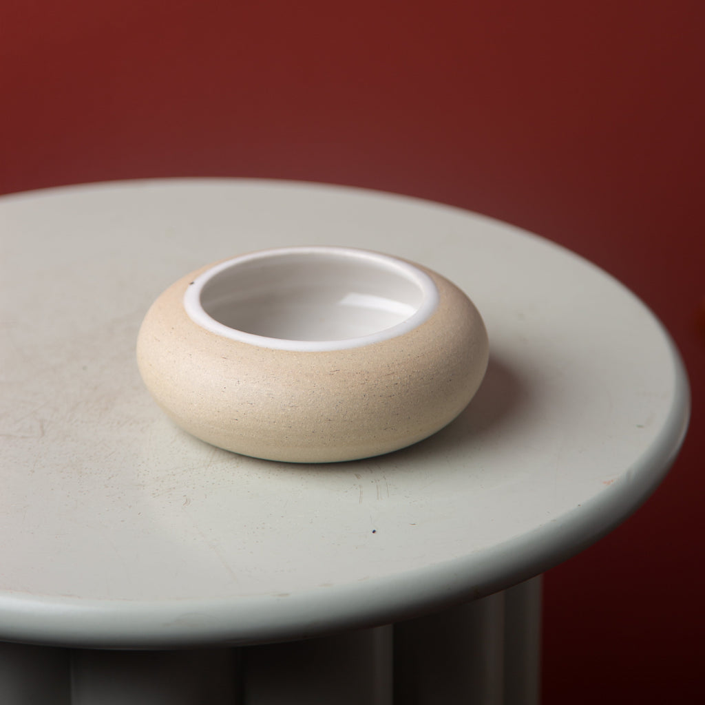 Small ceramic ikebana bowl on a round surface with a red background