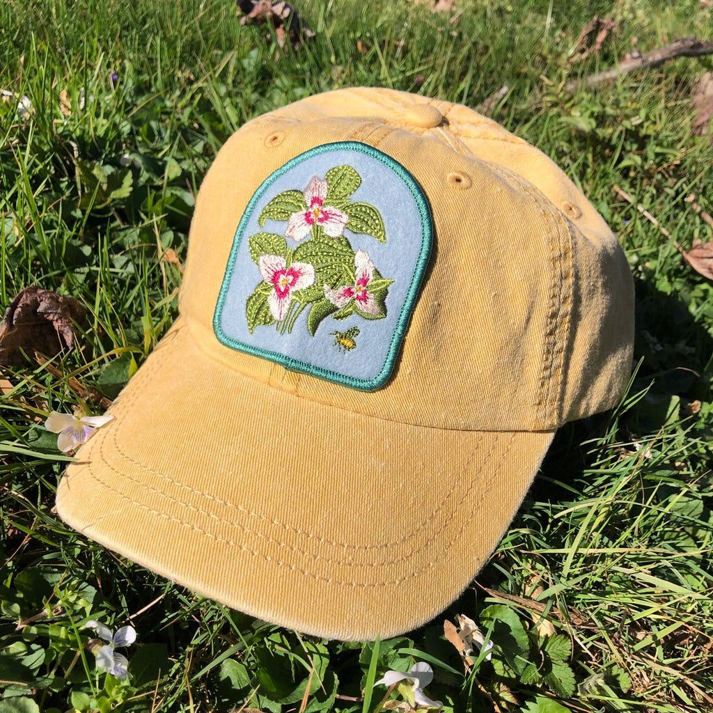 Yellow cap with a floral trillium native flower patch 